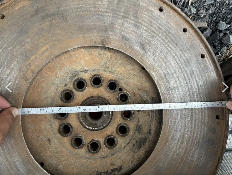 Measuring the diameter of a used flywheel with a tape measure for spare part identification